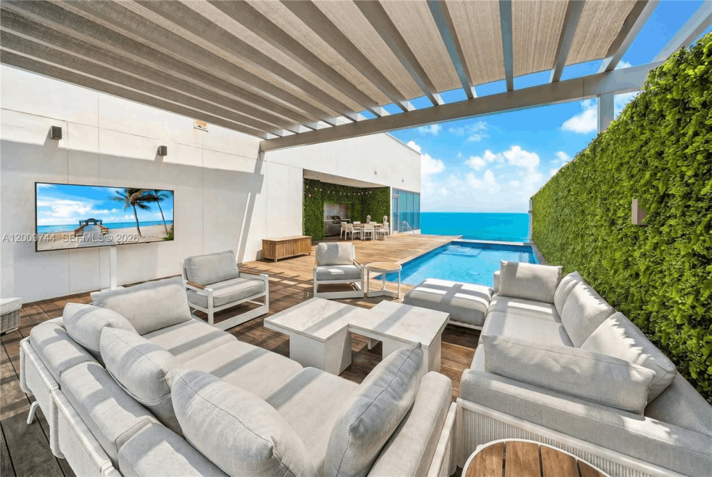 Luxury outdoor living space at a Coral Ridge waterfront home featuring a private pool, covered patio, ocean views, and modern resort-style amenities.