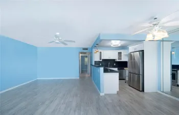 Light filled living room features hardwood-style flooring and a sleek kitchen with stainless steel appliances-an ideal setting for entertaining.