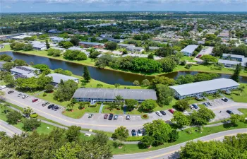 Scenic aerial of building framed by a waterfront view & lush greenery.