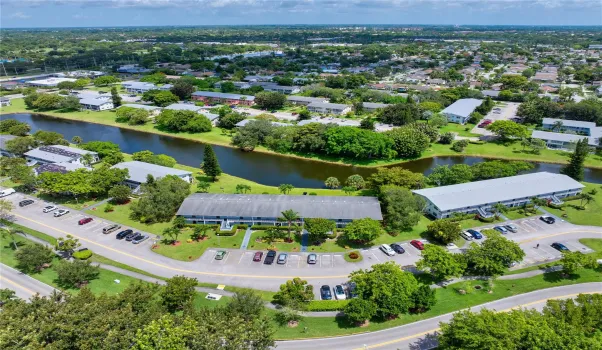 Scenic aerial of building framed by a waterfront view & lush greenery.