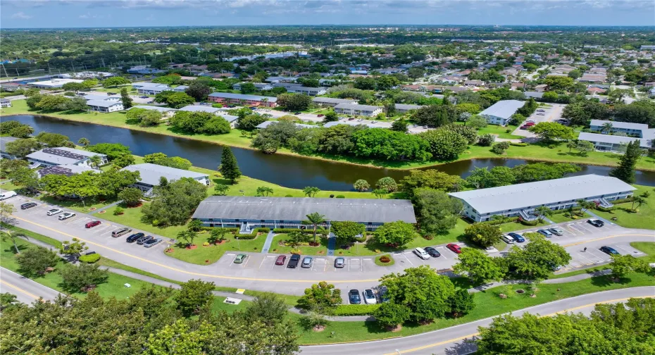Scenic aerial of building framed by a waterfront view & lush greenery.