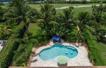 Custom pool with travertine deck, private fenced yard, lush tropical landscaping