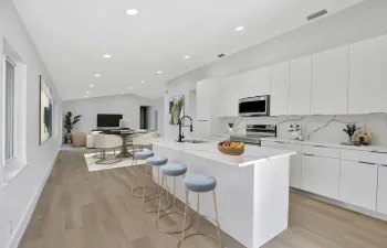 Virtually Staged. Kitchen/island with dining area and living room in the background.