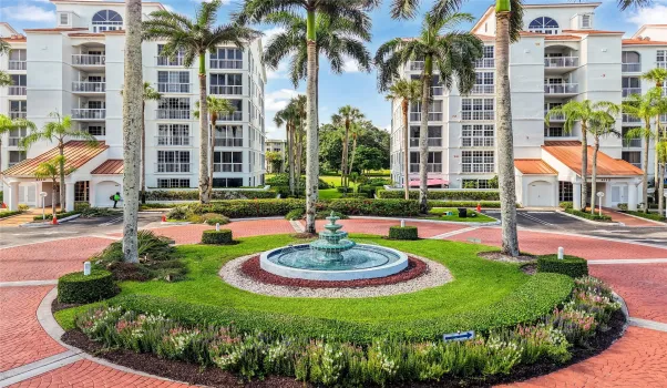 Well-maintained grounds with a central fountain, tropical landscaping, and secure building entrances offer a welcoming first impression.