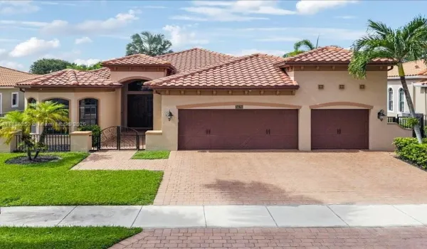 Grand façade featuring timeless architectural design, spacious three-car garage, and paver driveway.