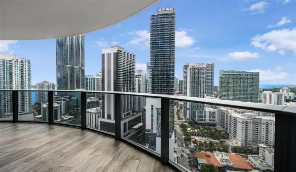 Bright open-concept dining and living space with floor-to-ceiling windows, upgraded marble kitchen island, and panoramic Brickell skyline and bay views. Seamless layout connecting to the expanded primary suite and kitchen area.