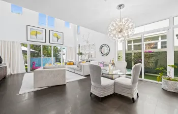 Living room with 20ft ceilings overlooking the backyard with heated pool and waterfall