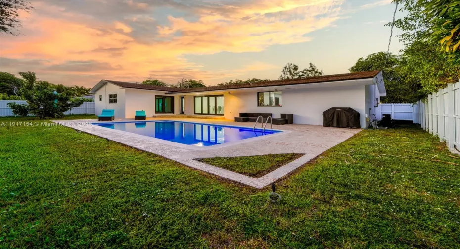 Spacious fenced backyard with resurfaced pool, patio seating, and multiple access points to the home.