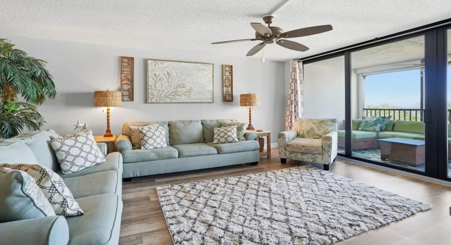 Living Room with 2 couches, chair, end tables, rug, TV stand, and a custom wood panel.