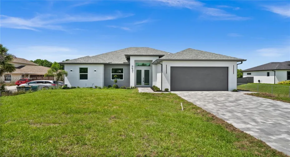 Prairie-style house with decorative driveway, a
garage, stucco siding, and roof with shingles