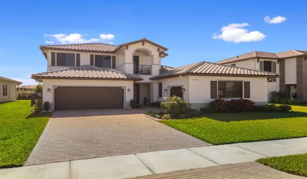 Mediterranean / spanish house with a front lawn, a balcony, decorative driveway, and stucco siding