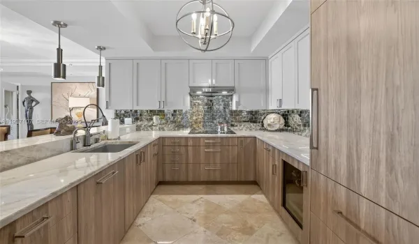 Spectacular kitchen w/ custom bleached walnut veneer cabinetry by renowned Chicago based millworker. Grain matches from top to bottom. Taj mahal quartzite. Wolf induction cooktop & double oven (w/ microwave / convenction at top oven), Sub Zero Refrigerator & Beverage Cooler, Miele Dishwasher.  Sink w/ touchless Brizo faucet, including water filtration faucet. Antiqued mirror backsplash. Wide hallway to bedrooms, bathrooms and laundry room. through archway
