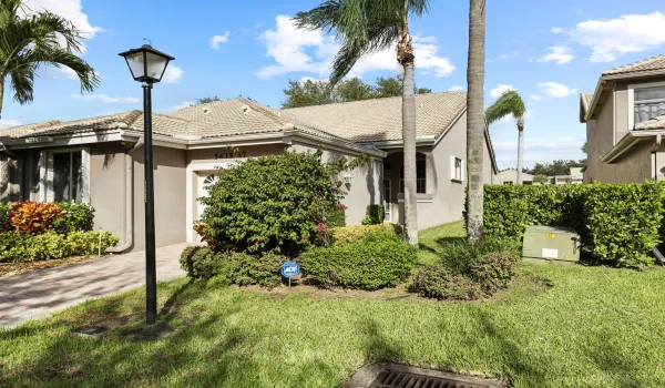 Charming villa entrance with a private paver driveway and lush tropical landscaping that creates a warm, inviting first impression. Nestled within Monterey Lake, this residence offers a quiet, tucked-away feel with swaying palms and beautifully maintained greenery welcoming you home.
