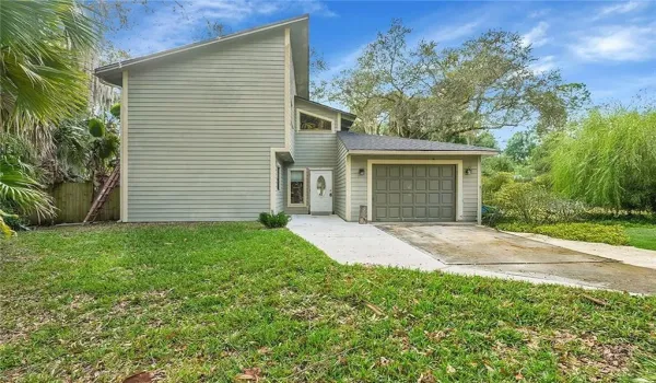 View of side of property featuring an attached garage and concrete driveway