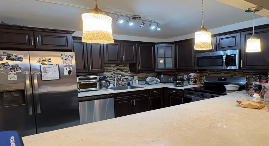 Open kitchen with new stainless steel appliances.