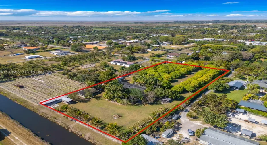2.5 Acre Agricultural exemption property w/ 4/2 home, 6 car garage, guest studio, saloon, barn, chicken coop, & Lychee grove. THE CANAL IS IN THE REAR YARD THE GROVE UP FRONT HOUSE SURROUNDED BY TROPICAL PLANTS .. GREAT COLOR. TREES LOADED W ORCHIDS