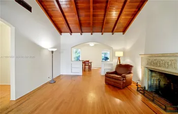 Bright living room with wood-beam ceiling, fireplace, and natural light in updated 33138 home