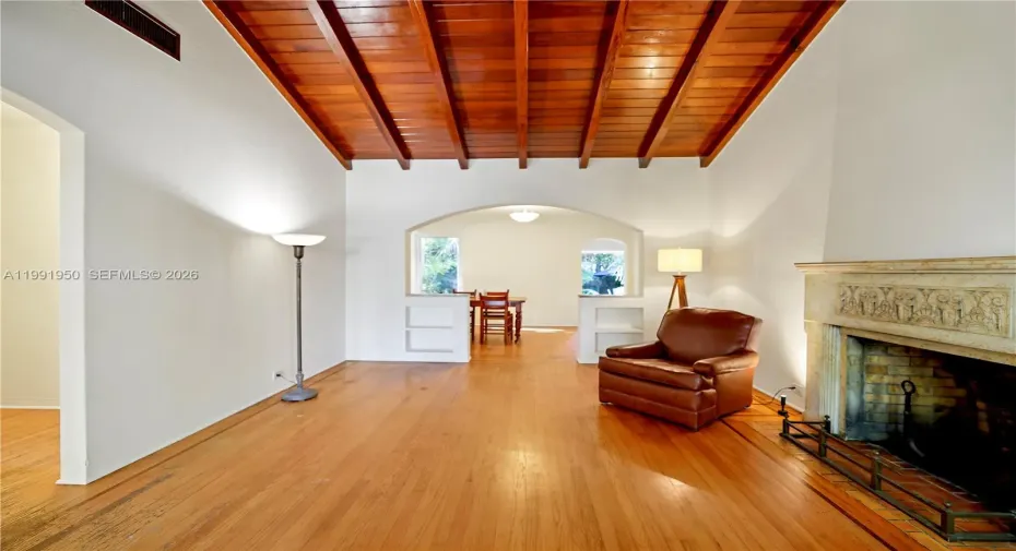 Bright living room with wood-beam ceiling, fireplace, and natural light in updated 33138 home