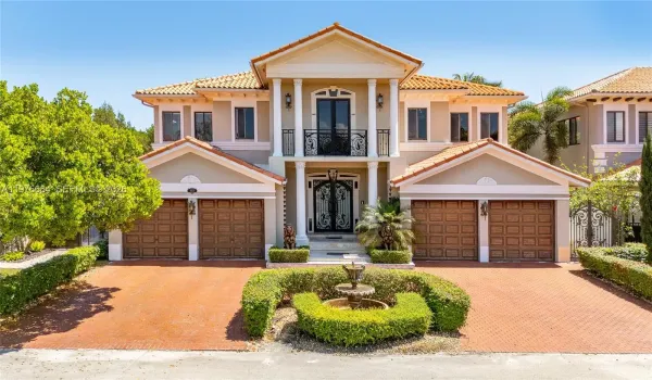 Stunning Mediterranean-style estate boasting grand curb appeal with a symmetrical facade, soaring pillared entryway, and elegant wrought-iron accents. This impressive residence features a spacious brick-paved driveway, two double garages, and professional landscaping centered around a classic tiered fountain.