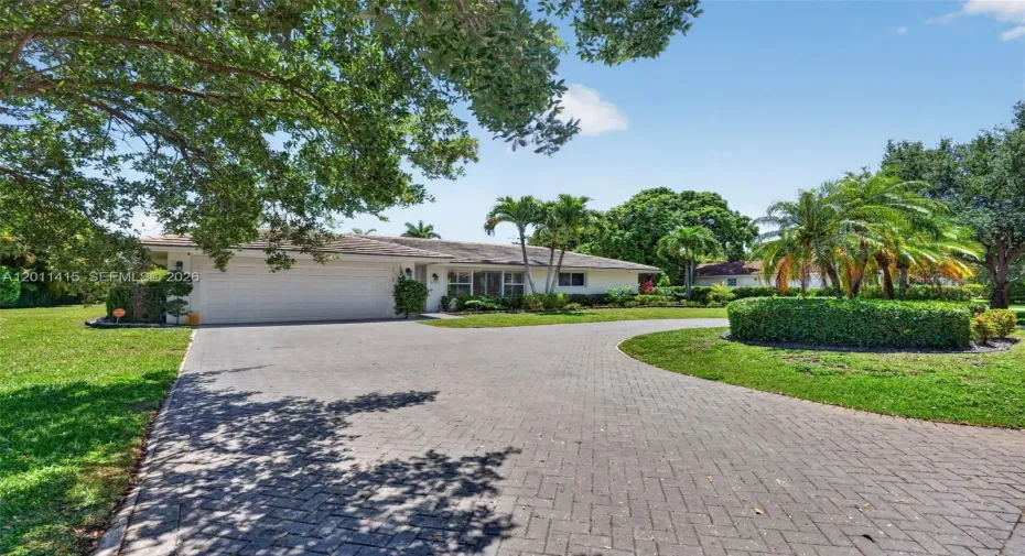 Home features a welcoming circular driveway leading to a 2-car garage, all set on an oversized lot,