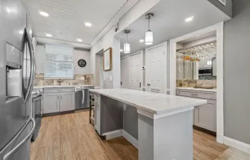 Updated and open kitchen boasts shaker style cabinets, quartz countertops and stainless steel appliances