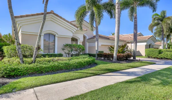 Lush landscaping, tall palms, and a stately entry set the tone for this private country club residence.