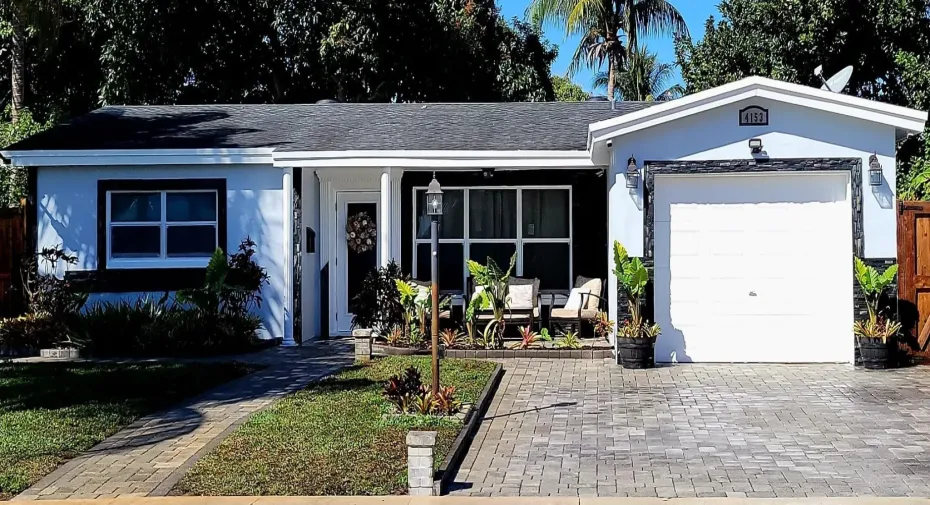 Charming single-story home with paved driveway, attached garage, and inviting front porch.
