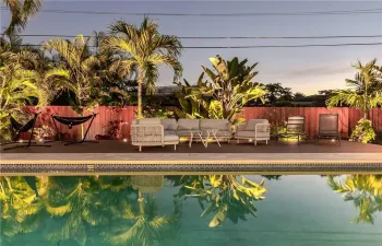 Tropical Fenced in Private Backyard with Heated Pool, uplighting, outdoor dining table, lounge chairs and plenty of seating/hammocks.