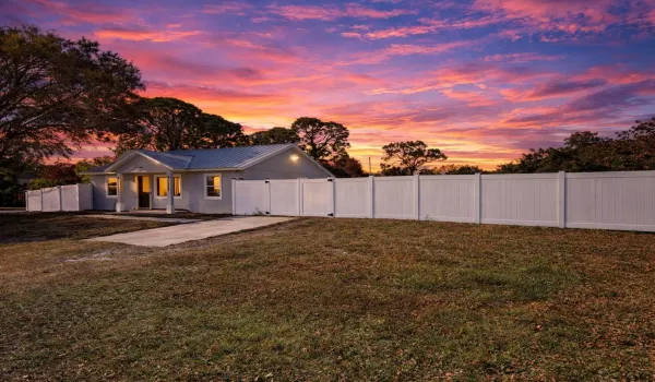 front of property at dusk with a metal roof and view of fenced in yard