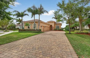 Beautiful tropical home with paver driveway, lush landscaping, and inviting curb appeal throughout neighborhood quiet