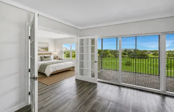 Second Bedroom features French doors opening directly to the living area, creating flexible use for guests, a home office, or additional living space. Vinyl flooring and large windows provide a bright, airy feel with scenic green space views nearby. Photo has been virtually staged for illustrative purposes. Furniture and decor shown are digitally added.