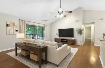 Living room with cathedral ceilings, ceiling fan, track lighting, and sliding glass doors leading to a covered and screened balcony. This image has been virtually staged to illustrate potential furniture placement and use of space.