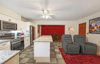 Open-concept living area with cozy seating, granite island, and beach accents—ideal for seasonal comfort.