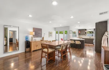 Open dining area with laminate wood plank flooring, recessed lighting, and direct connection to the kitchen and outdoor courtyard access.