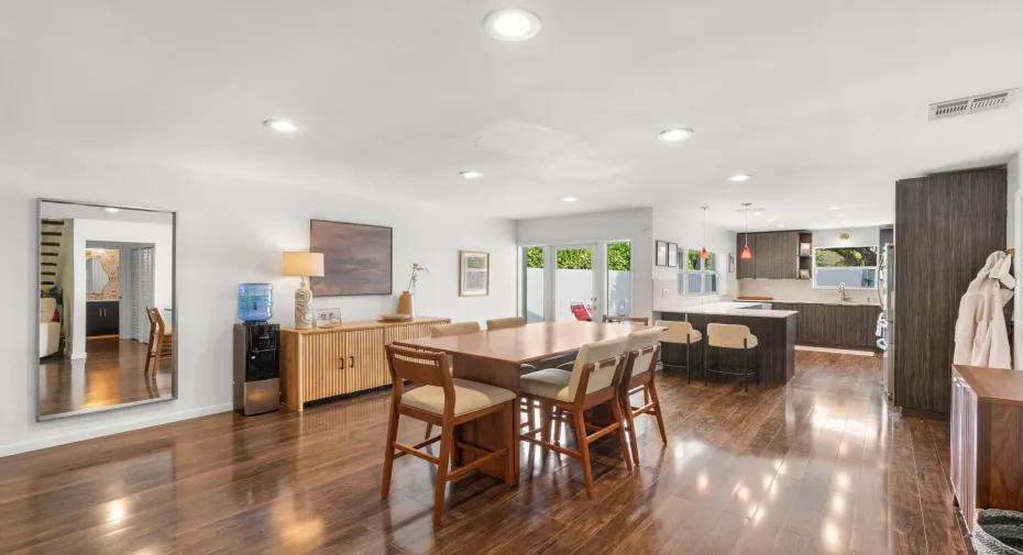 Open dining area with laminate wood plank flooring, recessed lighting, and direct connection to the kitchen and outdoor courtyard access.
