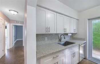 Kitchen to hallway and two bedrooms. Polished terrazzo floors throughout.