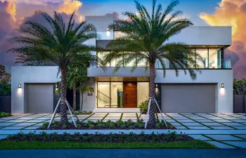 A striking modern façade framed by towering palms and clean architectural lines, illuminated beautifully at twilight. Sleek and sophisticated, this residence makes a bold statement with seamless indoor-outdoor flow and refined contemporary design.