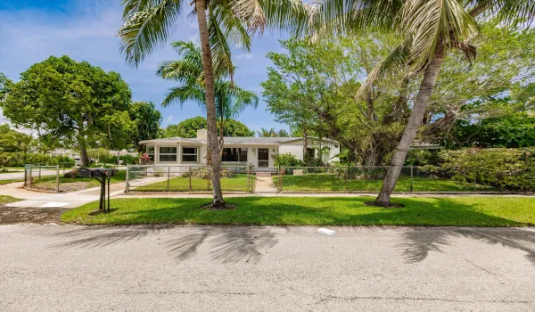 West-facing home in West Palm Beach with inviting curb appeal, framed by mature coconut, avocado, palm, and magnolia trees—offering a true South Florida lifestyle—offering a true South Florida lifestyle.