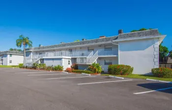 Two-story building with a stucco exterior, gray shingle roofing, and white balustrade balconies