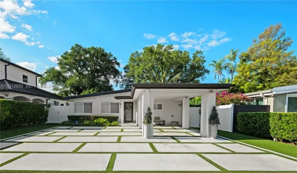 Fully concrete front yard with large-format pavers, artificial turf grid, and privacy landscaping — one-car covered carport with white concrete columns. Schenley Park, Miami FL 33155.