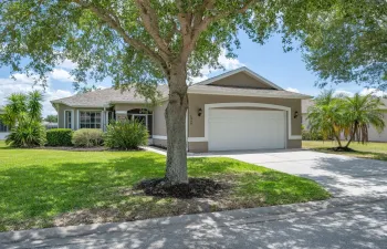 Exterior featuring a two-car garage, concrete driveway, and mature landscaping