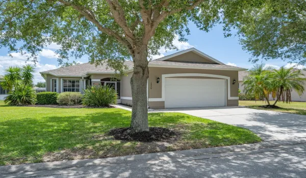 Exterior featuring a two-car garage, concrete driveway, and mature landscaping