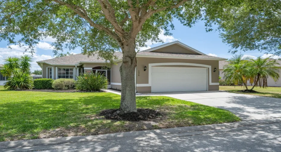 Exterior featuring a two-car garage, concrete driveway, and mature landscaping