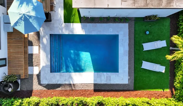 Resort-style heated pool surrounded by turf, privacy landscaping, and multiple lounging areas for the ultimate South Florida outdoor living experience.