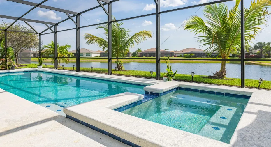 The “million-dollar” view... pool, spa, and lake framed by swaying palms under a panoramic screen enclosure.