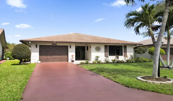 Front of home with long driveway and beautifully landscaped