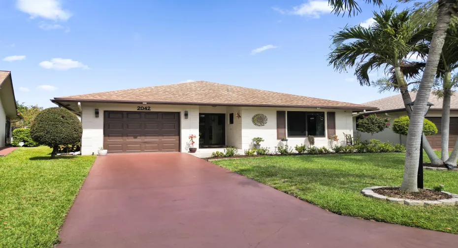 Front of home with long driveway and beautifully landscaped