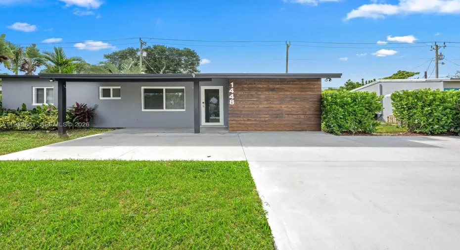This is your next home with a striking modern exterior with refined curb appeal, featuring a sleek architectural façade, designer wood-accent entry, and manicured landscaping. A wide concrete driveway and clean contemporary lines set the tone for this move-in-ready residence, offering a perfect blend of modern sophistication, privacy, and effortless South Florida living.