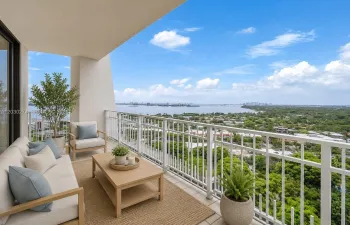 DIGITALLY STAGED BALCONY WITH VIEWS OF MIAMI WATERWAY AND LUSH GREEN SPACE.