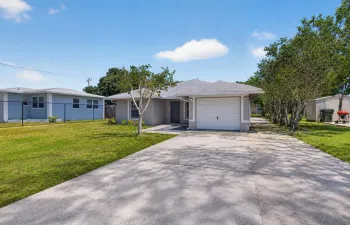 Lovely property featuring an oversized driveway, mature trees, and inviting curb appeal